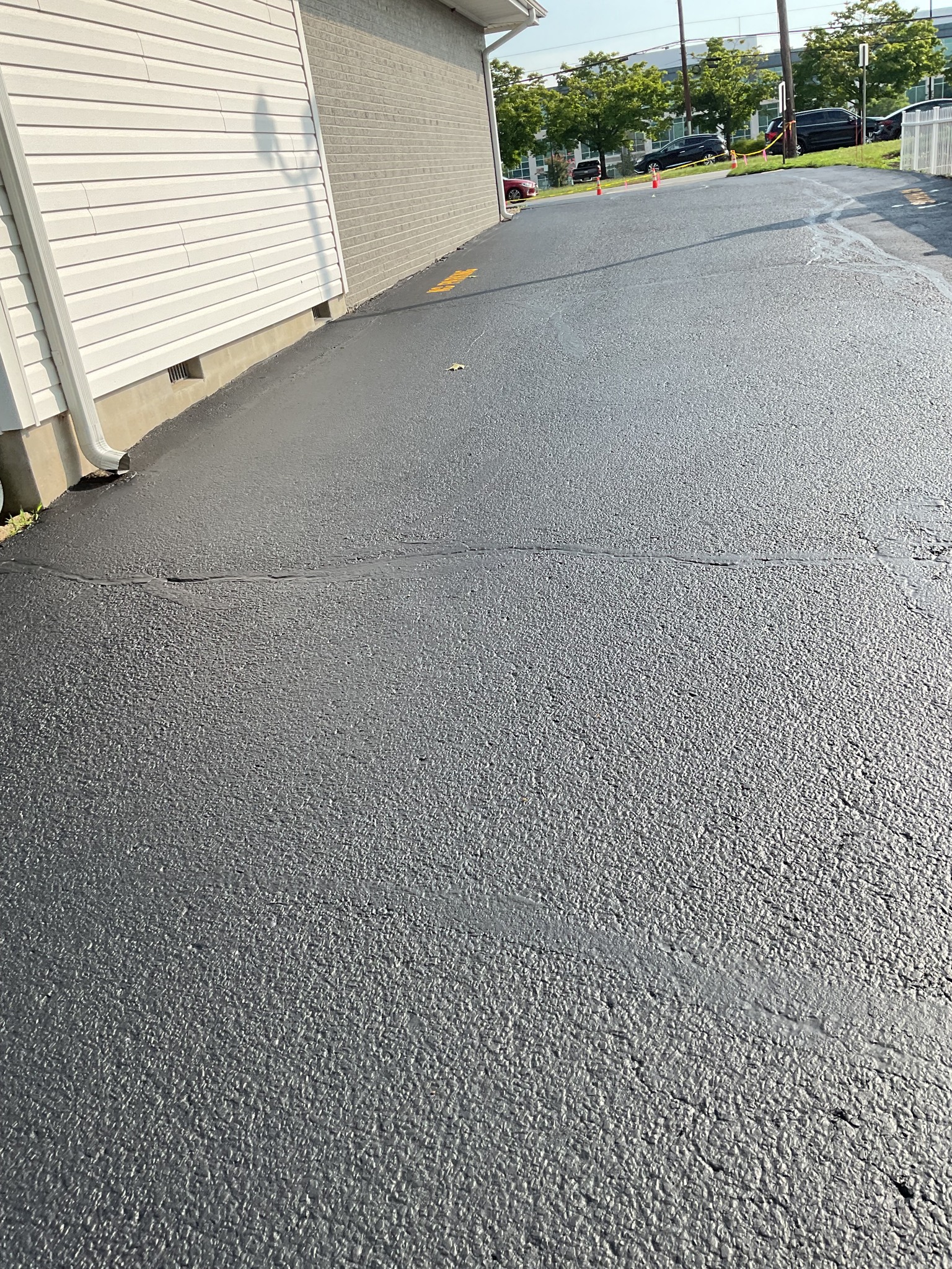 Freshly sealed asphalt surface beside a building